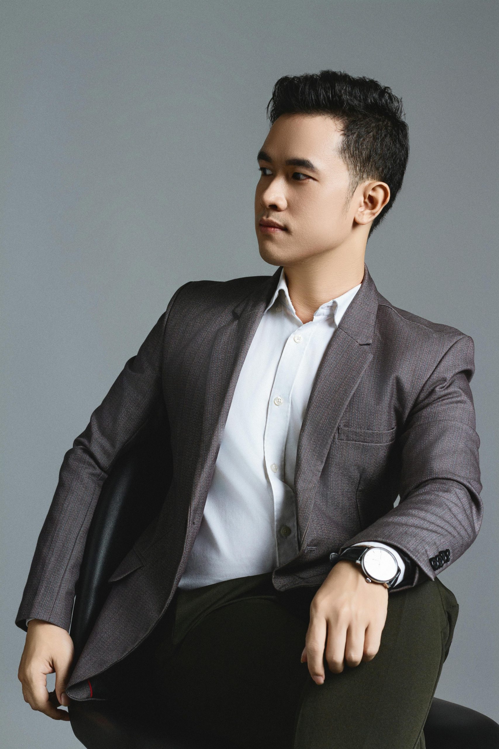 Well-dressed man in a suit posing elegantly in a studio setting.