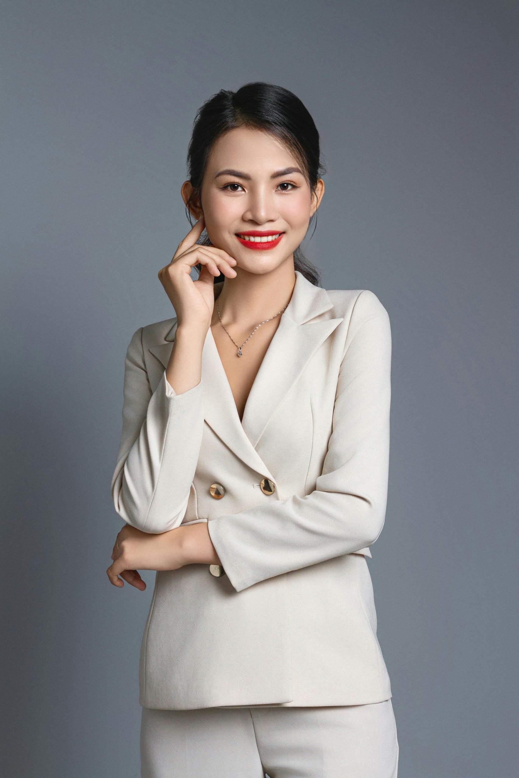 Portrait of a confident woman in a white suit posing in a studio setting.